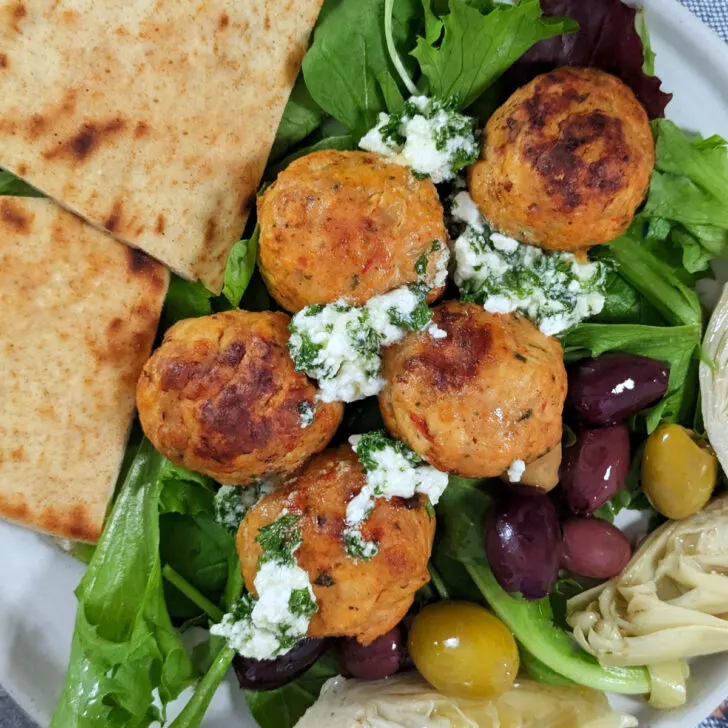 Harissa meatballs in a bowl with feta topping.
